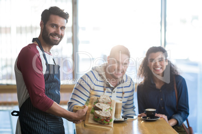 Waiter serving a plate of sandwich to customer in cafe