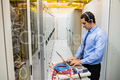 Technician in head phones using laptop