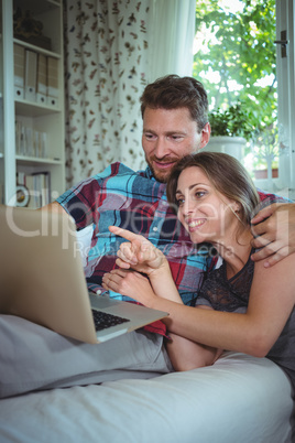 Happy couple using laptop in living room