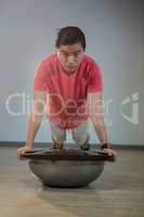 Man doing push-up on bosuball