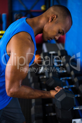 Athlete exercising with dumbbell in fitness studio