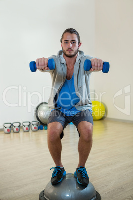 Man exercising with dumbbells on bosuball