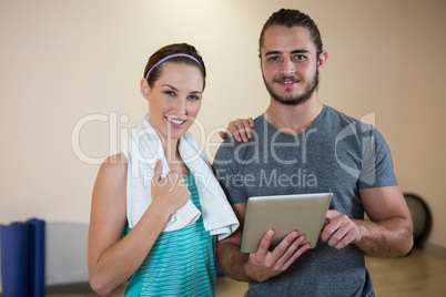 Portrait of fitness trainer and woman with digital tablet