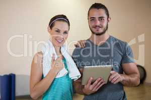 Portrait of fitness trainer and woman with digital tablet