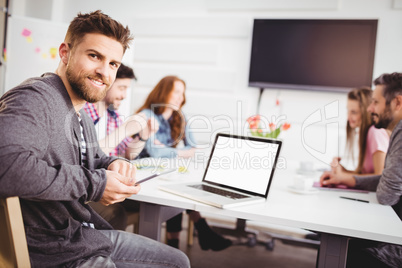 Portrait of confident businessman with cellphone at creative office