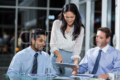 Businesswoman discussing with colleagues over digital tablet