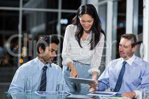 Businesswoman discussing with colleagues over digital tablet