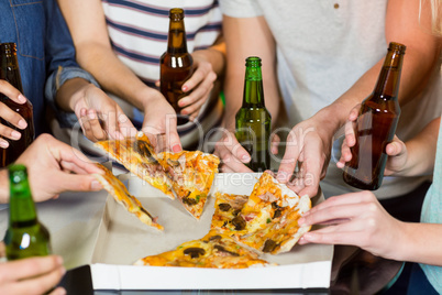 Group of friends having bottle of beer and pizza in party