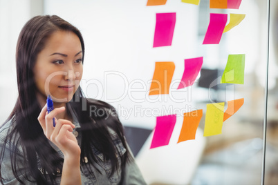 Confident creative businesswoman looking at multi colored sticky notes