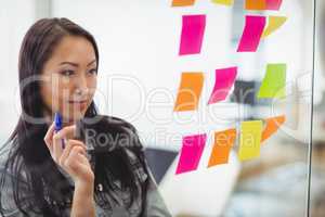 Confident creative businesswoman looking at multi colored sticky notes