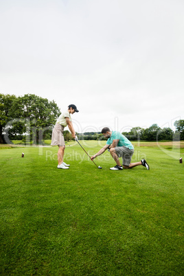 Male instructor assisting woman in learning golf