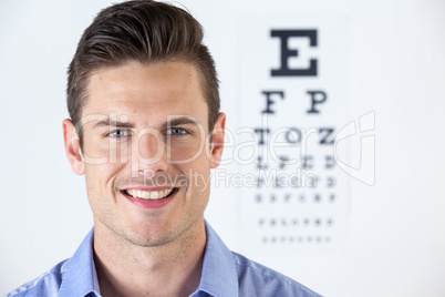Man wearing contact lens with eye chart in background