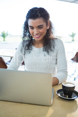 Woman using laptop and a coffee cup on the table in the coffee shop