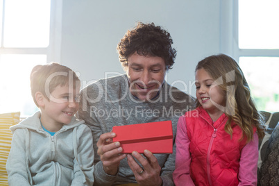 Father opening gift box with children