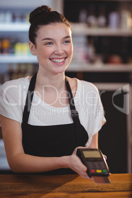 Smiling waitress showing credit card machine