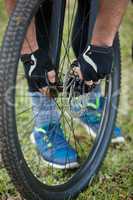 Male mountain biker examining front wheel of his bicycle