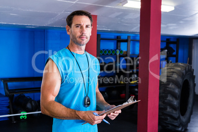 Serious fitness instructor holding clipboard