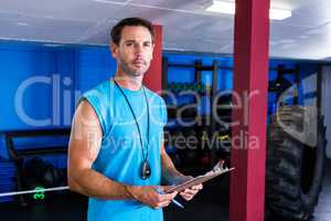 Serious fitness instructor holding clipboard