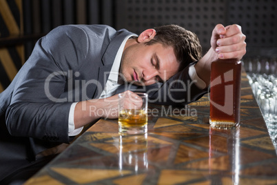 Drunk man lying on a counter with bottle of whisky