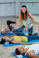 Yoga instructor helping student with leg flexes