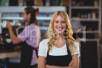 Portrait of smiling waitress standing with arms crossed