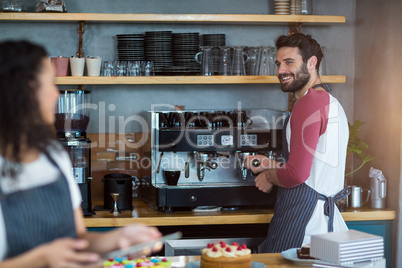 Waiter and waitress working in kitchen at cafÃ?Â©