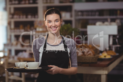 Portrait of waitress holding tray of coffee cups