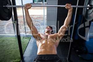 Shirtless man exercising with barbell