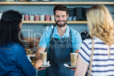 Waiter serving a cup of coffee to customer at counter