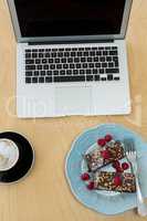 Delicious cakes, cup of coffee and laptop on table