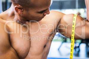 Man measuring biceps with tape measure