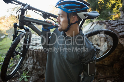 Male mountain biker carrying bicycle in the forest