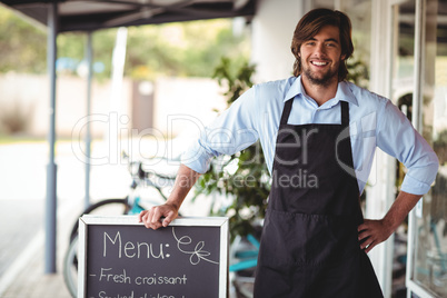 Waiter standing with menu board outside the cafe