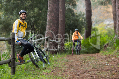 Male biker sitting on fence in countryside