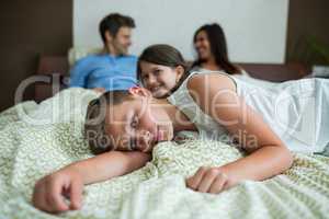 Family lying on bed in bedroom