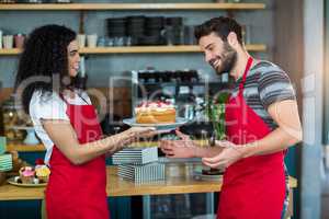 Smiling waitress giving a plate of cake to waiter