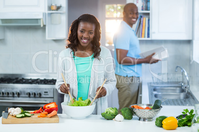 Woman preparing food while man standing in the background
