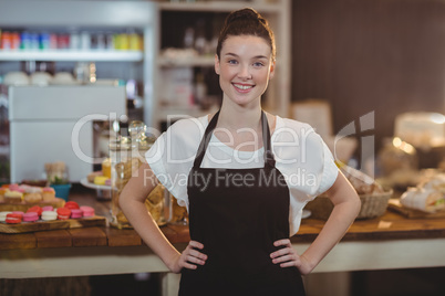 Portrait of smiling waitress standing with hands on hip