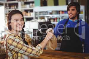 Woman receiving parcel from waiter at counter