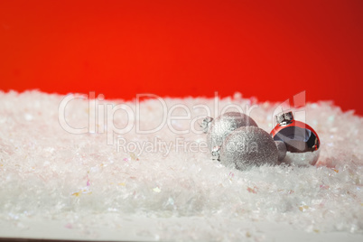 Three christmas baubles on snow