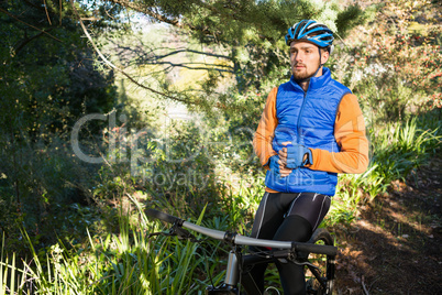 Male mountain holding water bottle standing with bicycle