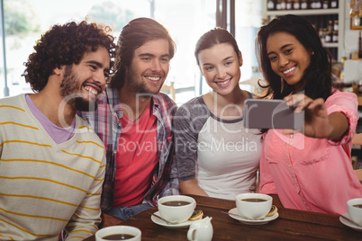 Group of friends taking a selfie while having cup of coffee