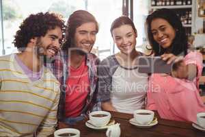Group of friends taking a selfie while having cup of coffee