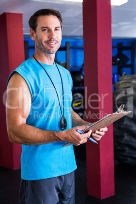 Smiling fitness instructor holding clipboard