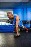 Male athlete lifting dumbbells in gym