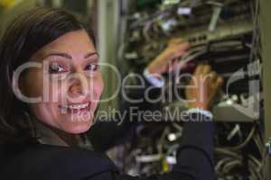 Portrait of technician checking cables in a rack mounted server