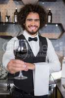 Bartender serving glass of red wine in bar counter