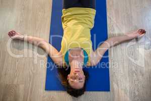 Woman doing yoga corpse pose on exercise mat