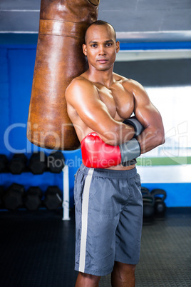 Confident male boxer standing by punching bag