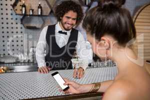 Waiter interacting with beautiful woman while using mobile phone